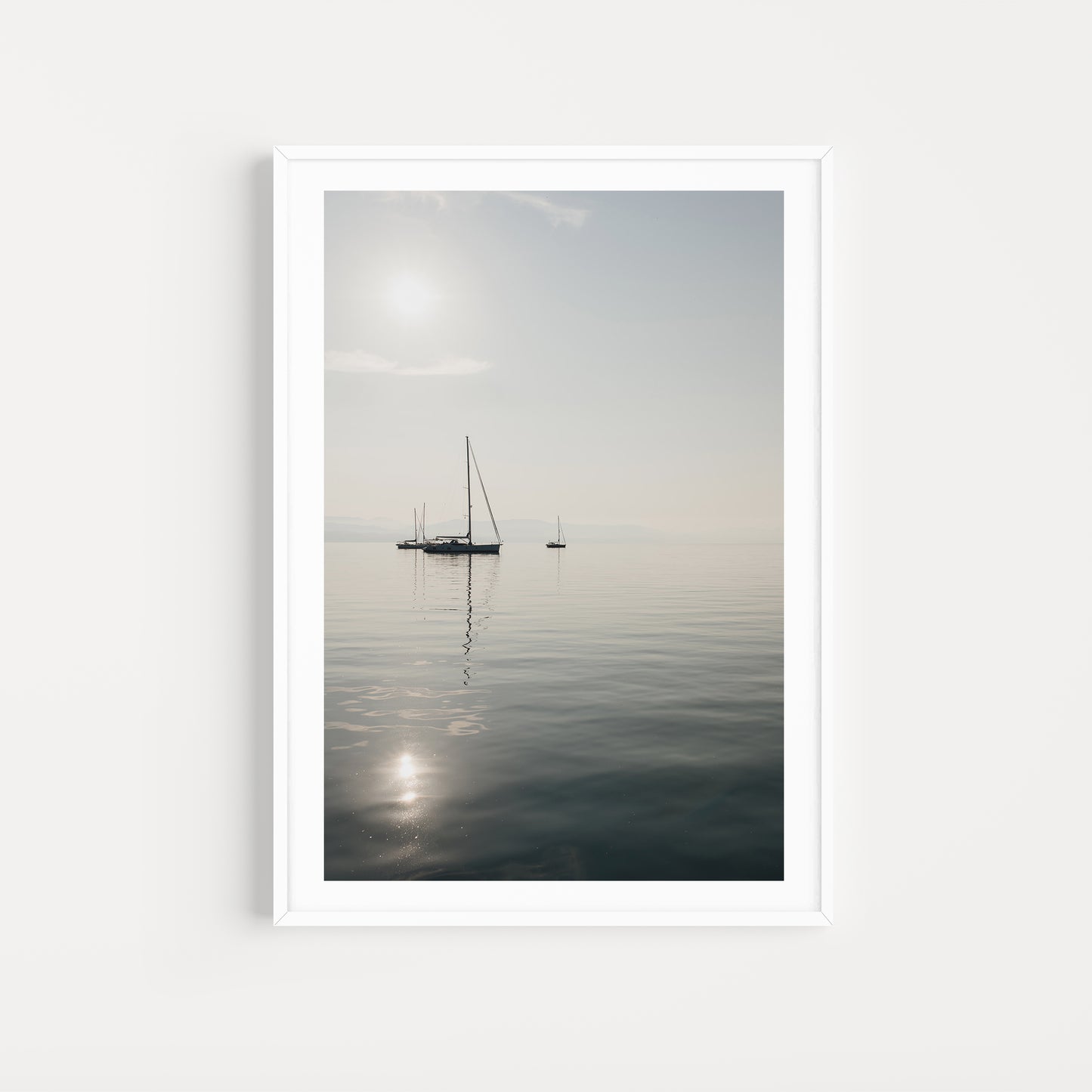 Framed artwork of a sailboat on a calm body of water with a white frame. SHOP Sailing Boat Fine Art Photographic Prints. Bring the calm of boats at anchor in your home with boats at anchor on the Aegean Sea. Sailing Wall Art.