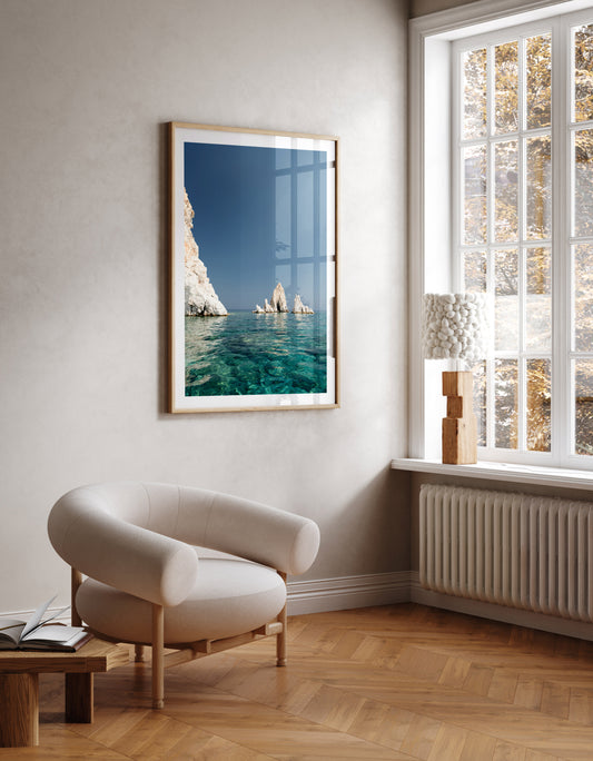 Greek Islands art print schowcasing vibrant blue portrait image of rocks at and ocean at Polyaigos Island near Milos. Wall art mock up of Greece fine art photographic print.