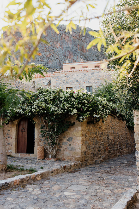 Photograph of a stone building with greenery on a white background. Greece wall art print collection boasts beautiful artwork featuring the beautiful coastal scenes of Monemvasia, Paros and more. Greece Photographic Wall Art.