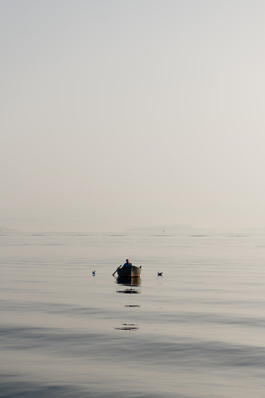Photographic artwork of a small boat on a calm body of water with a white frame. SHOP Mediterranean Wall Art Prints | Browse artfully captured and curated range of wall art and scenes from the Mediterranean. Mediterranean Fine Art Prints.