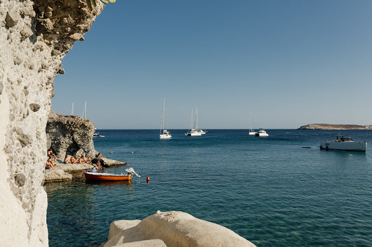 Photograph of a coastal scene with boats and cliffs. KIMOLOS ISLAND, CYCLADES, GREECE. SHOP Mediterranean Fine Art Prints with summer kissed scenes from Kimolos Island. Mediterranean Wall Art.