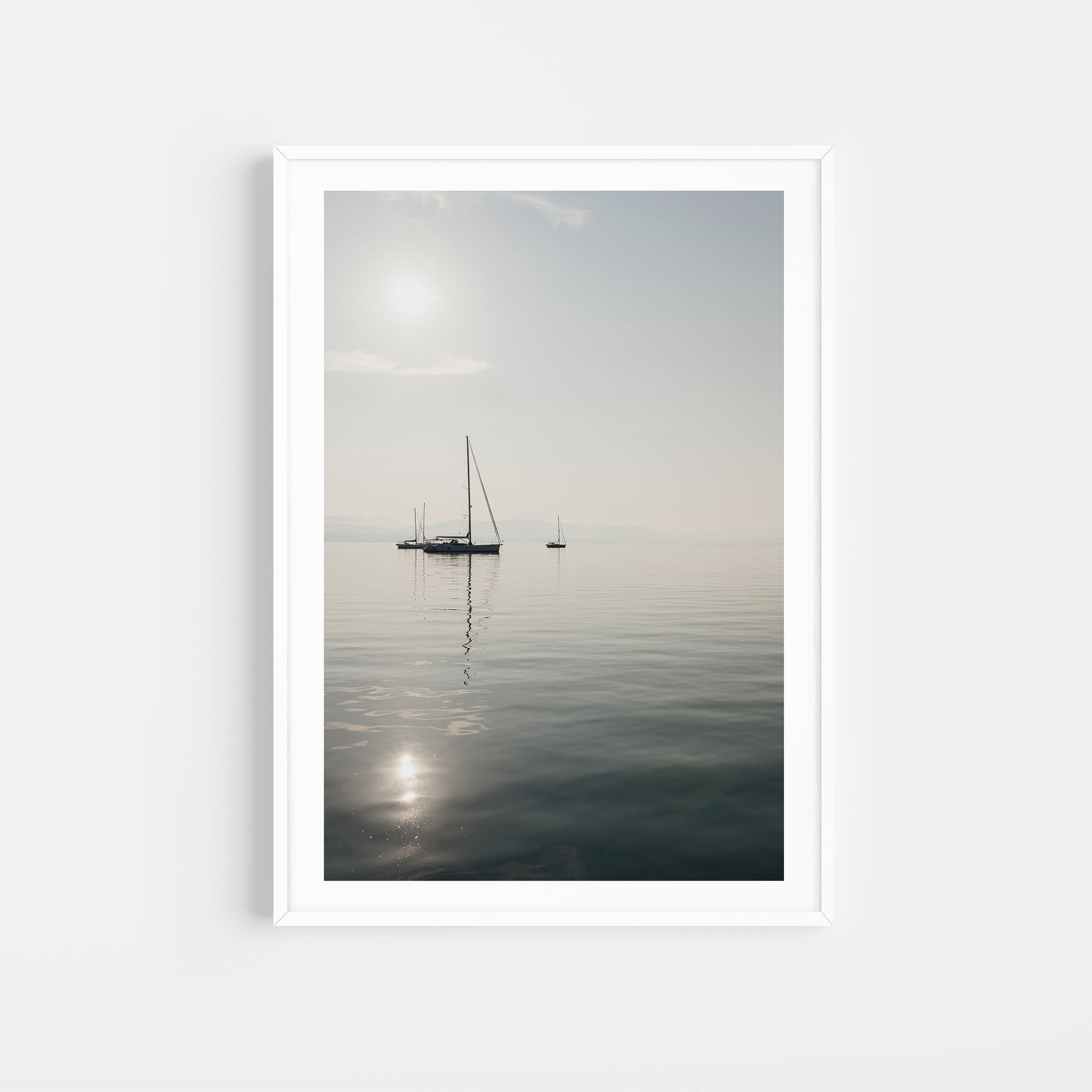 Framed artwork of a sailboat on a calm body of water with a white frame. SHOP Sailing Boat Fine Art Photographic Prints. Bring the calm of boats at anchor in your home with boats at anchor on the Aegean Sea. Sailing Wall Art.
