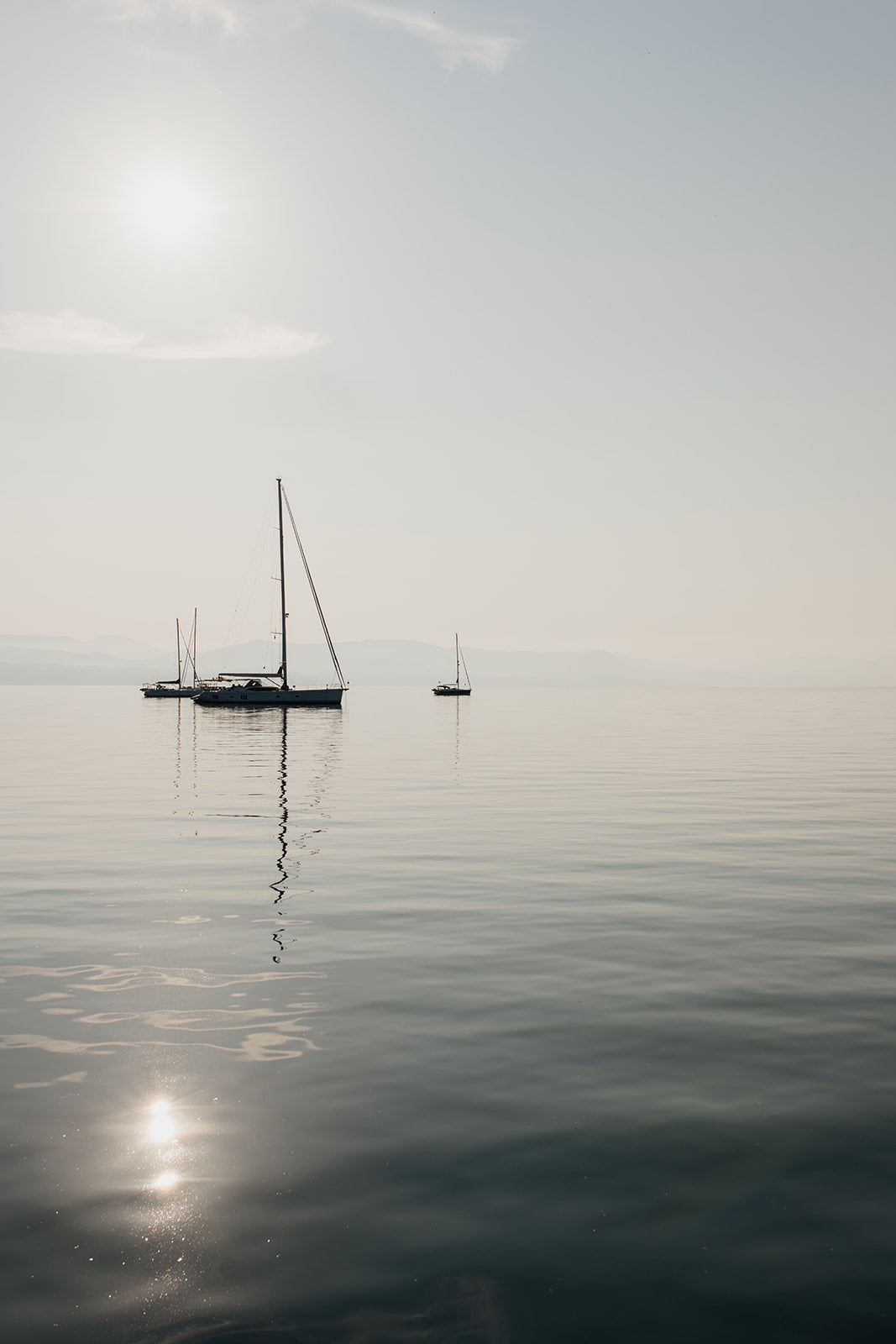 Photographic artwork of a sailboat on a calm body of water with a white frame. SHOP Sailing Boat Fine Art Photographic Prints. Bring the calm of boats at anchor in your home with boats at anchor on the Aegean Sea. Sailing Wall Art.