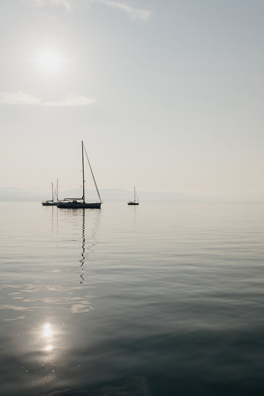 Photographic artwork of a sailboat on a calm body of water with a white frame. SHOP Sailing Boat Fine Art Photographic Prints. Bring the calm of boats at anchor in your home with boats at anchor on the Aegean Sea. Sailing Wall Art.