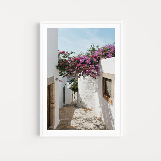 Narrow street with white walls and pink flowers in a Mediterranean setting. Bougainvillea Fine Art Photography Prints by Brooke Darling. Bring the floral dream of Greece into your home with Greek Island fine art photography prints.