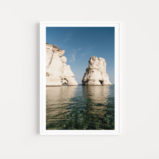 MILOS ISLAND, CYCLADES, GREECE | Shop Milos Island Art Photographic Prints, bring that vacation nostalgia into your home or space. Milos Fine Art Prints. 
Framed photograph of two large rock formations in a body of water with a clear blue sky.