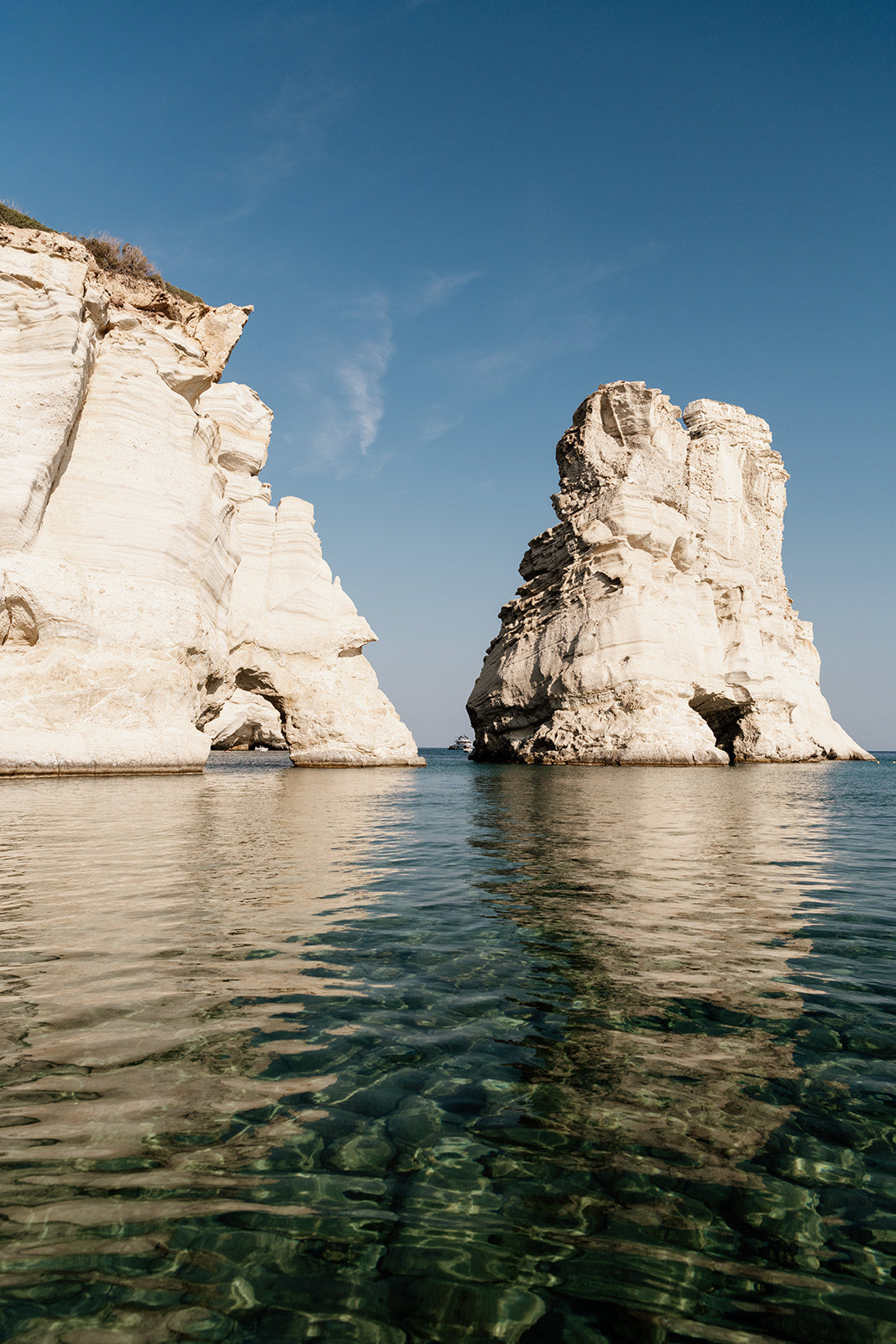 MILOS ISLAND, CYCLADES, GREECE | Shop Milos Island Art Photographic Prints, bring that vacation nostalgia into your home or space. Milos Fine Art Prints. 
Framed photograph of two large rock formations in a body of water with a clear blue sky.