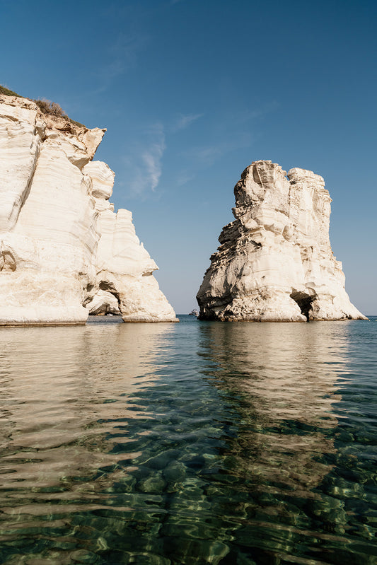 MILOS ISLAND, CYCLADES, GREECE | Shop Milos Island Art Photographic Prints, bring that vacation nostalgia into your home or space. Milos Fine Art Prints. 
Framed photograph of two large rock formations in a body of water with a clear blue sky.