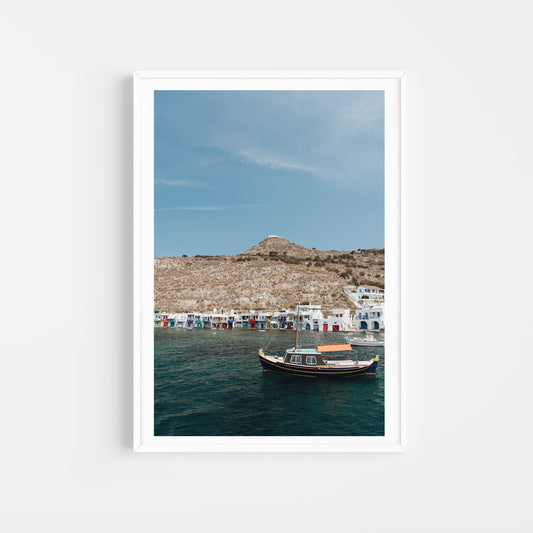 Framed photograph of a coastal scene with a boat in the water and a mountainous landscape. MILOS ISLAND, GREECE | SHOP Milos Photography Prints, bring the summer and colour of Greece into your home. Milos Photography Art Prints.