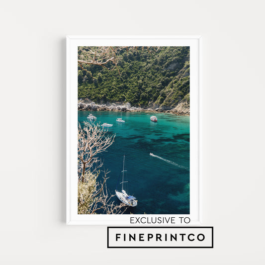 Framed artwork of a coastal scene with boats and greenery, exclusive to Fineprintco. Fine art travel prints are custom printed and framed to order. With premium printing and framing your investment can be enjoyed for years to come. Greece Wall Art.