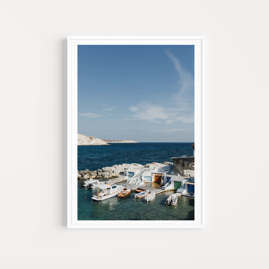 Framed photograph of a coastal scene with boats and a clear blue sky. MILOS ISLAND, CYCLADES, GREECE. SHOP Milos Fine Art Photography Prints. Bring summer love and vibes into your home with Milos Framed Wall Art. 