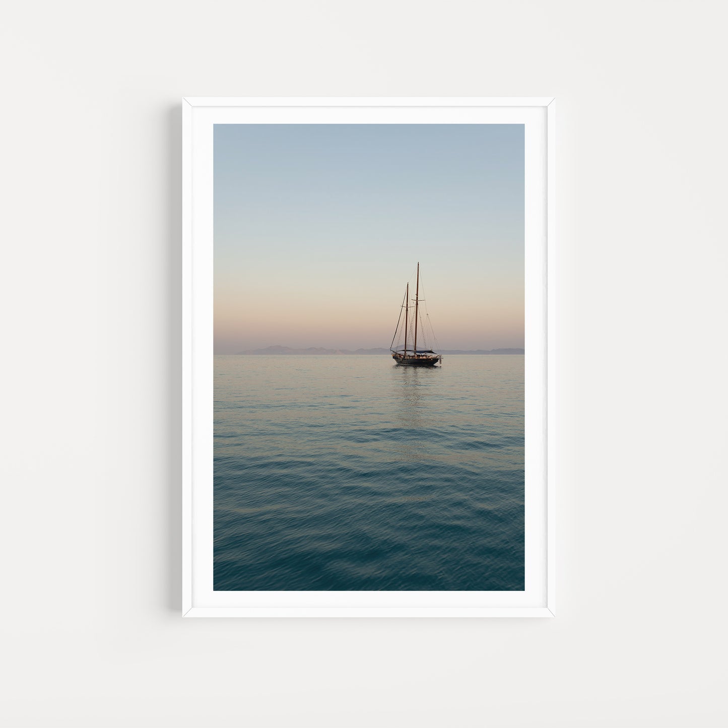 Framed artwork of a sailboat on calm water with a gradient sky. Mediterranean Fine Art Photography Prints. Greece Wall Art, adorn your walls with sailing scenes from the Greek Islands. Sailing Art Prints.