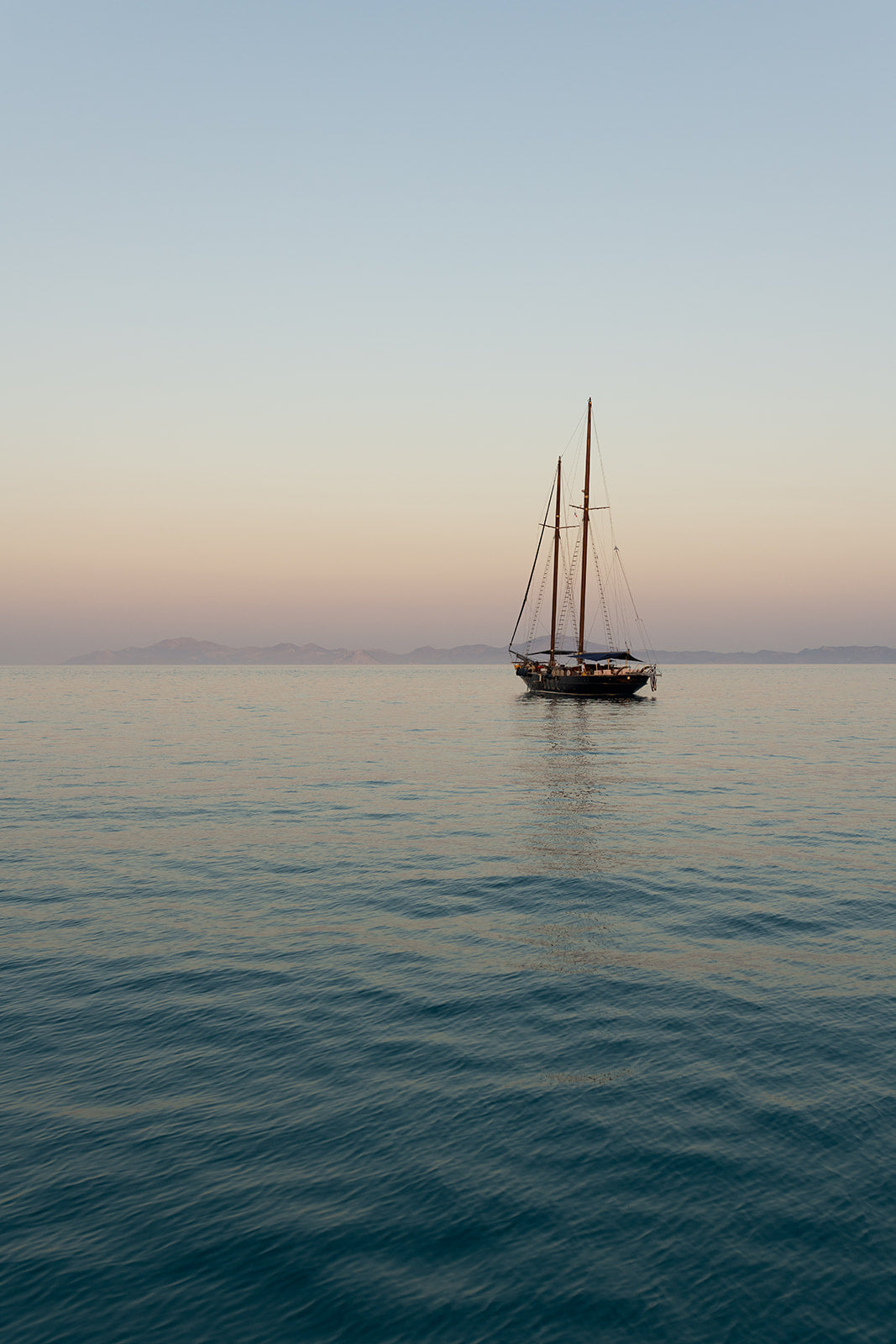 Photographic artwork of a sailboat on calm water with a gradient sky. Mediterranean Fine Art Photography Prints. Greece Wall Art, adorn your walls with sailing scenes from the Greek Islands. Sailing Art Prints.