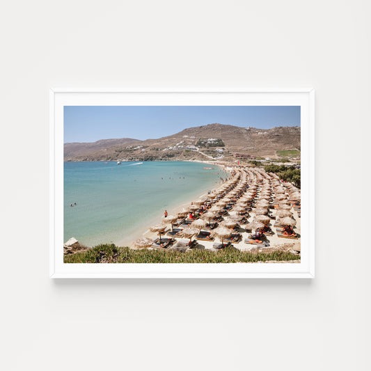 Beach scene with rows of umbrellas and mountains in the background. Mykonos Beach Club Wall Art Prints.
