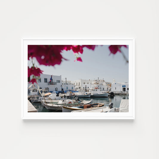 Greek Island fine art print in landscape format featuring Naoussa Boat Harbour, Paros Island with mock up in white frame on blank white wall. 