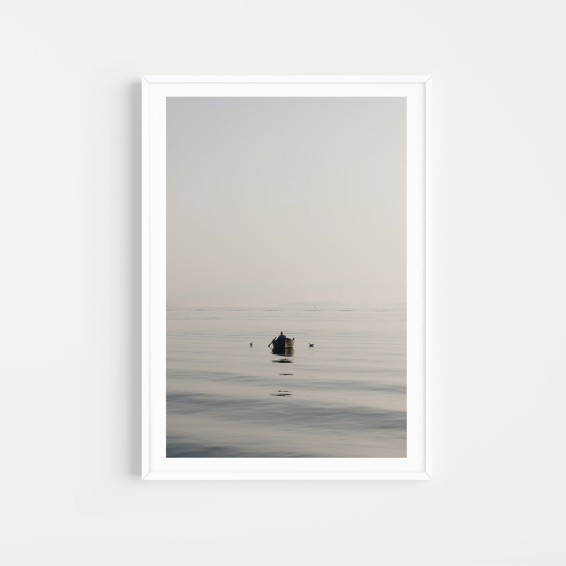 Framed artwork of a small boat on a calm body of water with a white frame. SHOP Mediterranean Wall Art Prints | Browse artfully captured and curated range of wall art and scenes from the Mediterranean. Mediterranean Fine Art Prints. 