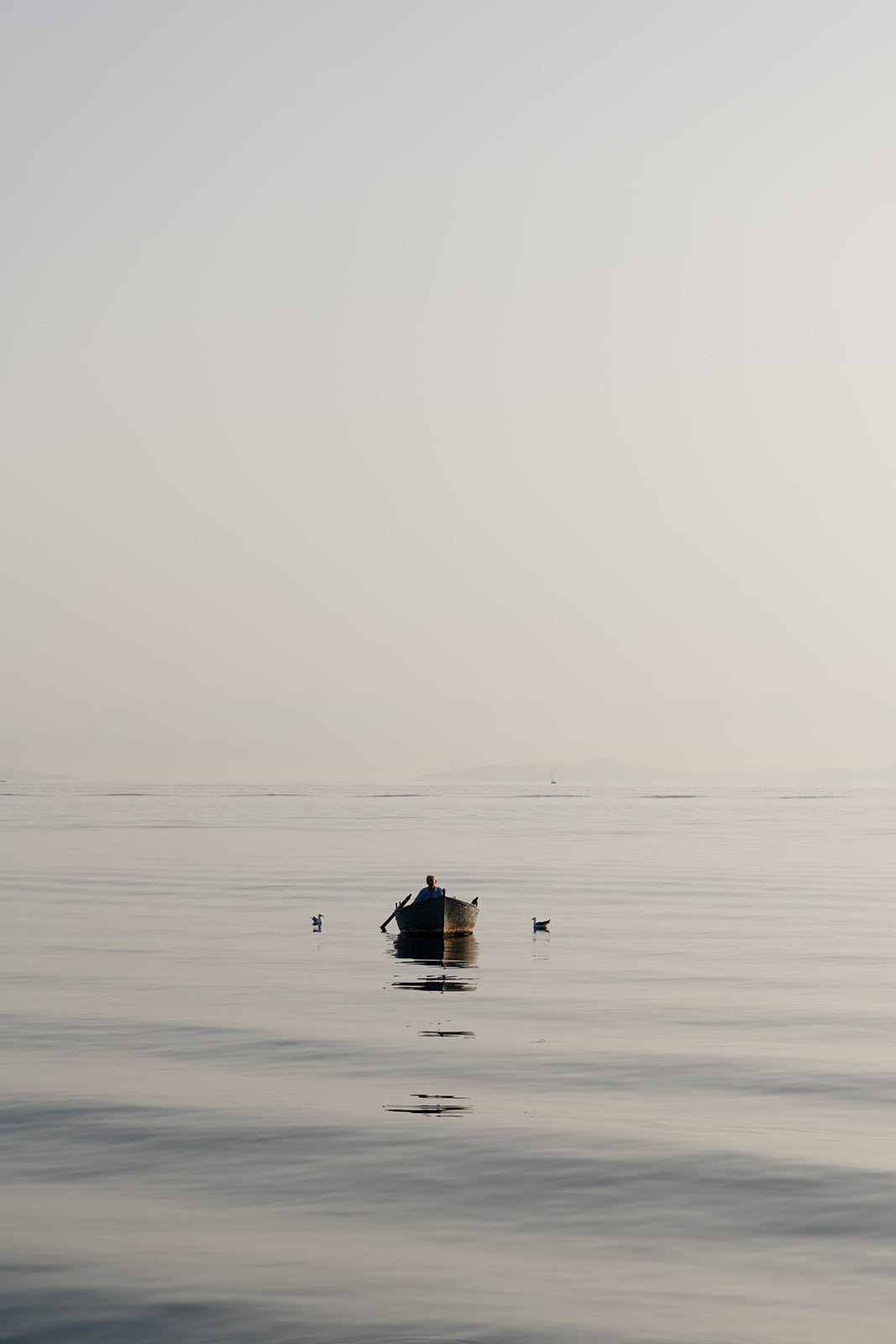 Photographic artwork of a small boat on a calm body of water with a white frame. SHOP Mediterranean Wall Art Prints | Browse artfully captured and curated range of wall art and scenes from the Mediterranean. Mediterranean Fine Art Prints. 