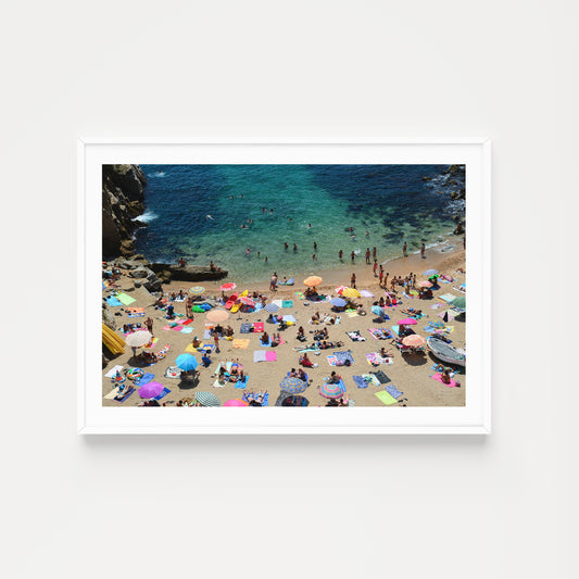 Beach scene with people and colorful umbrellas on a sandy shore with clear blue water. Buy Spain photographic prints in limited edition from Brooke Darling's exclusive collection. Coastal Spain fine art photography prints. Spain Wall Art.