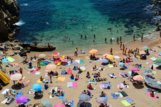 Beach scene with people and colorful umbrellas on a sandy shore with clear blue water. Buy Spain photographic prints in limited edition from Brooke Darling's exclusive collection. Coastal Spain fine art photography prints. Spain Wall Art.