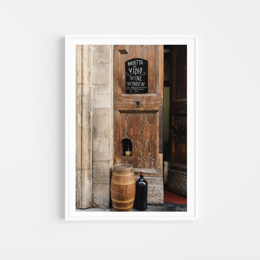 Wooden door with a sign and wine barrel in front, framed. FLORENCE, TUSCANY, ITALY | SHOP Tuscany Photographic Wall Art Prints. Transport yourself into the heart of wine culture with this Wine Art Photography Print. 