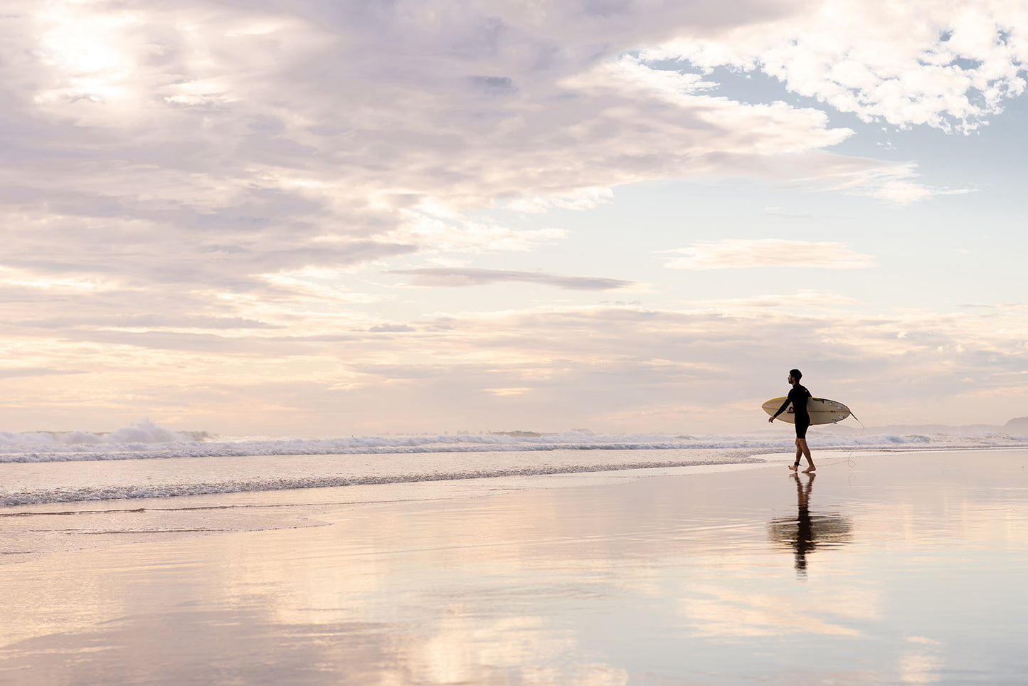 Coastal Australian fine art print featuring surfer walking along glassy sand on a Queensland beach at sunrise. Available in a white frame, landscape format and sold as a coastal Australian fine art print. 